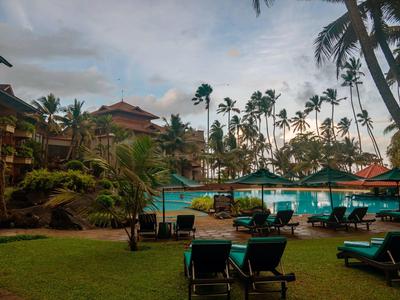 Hotelzwembad met ligstoelen en tropische begroeiing bij schemering