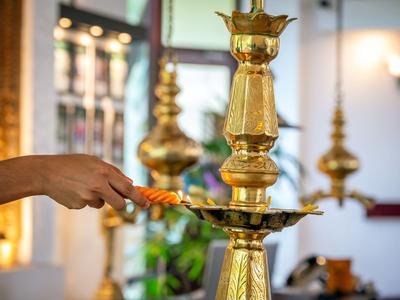 Hand hält eine brennende Fackel und zündet eine goldene Deckenlampe an.