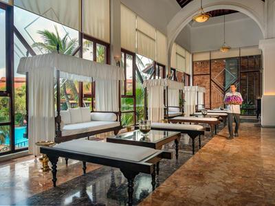 Elegante hotel-loungemeubels met dagbedden en kussens naast grote ramen en marmeren vloer.