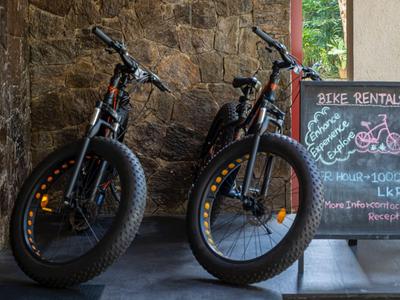 Zwei schwarze Fahrräder mit dicken Reifen neben einer Tafel mit Fahrradverleihinformationen.