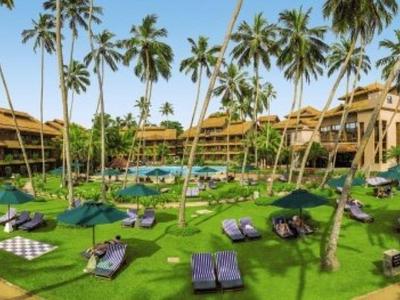 Groot tropisch hotelcomplex met zwembad, ligstoelen en veel palmbomen