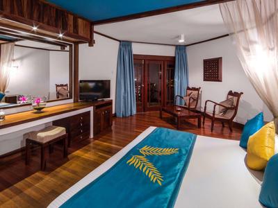 Gezellige hotelkamer met houten vloer, groot bed, tv en zithoek met stoelen.