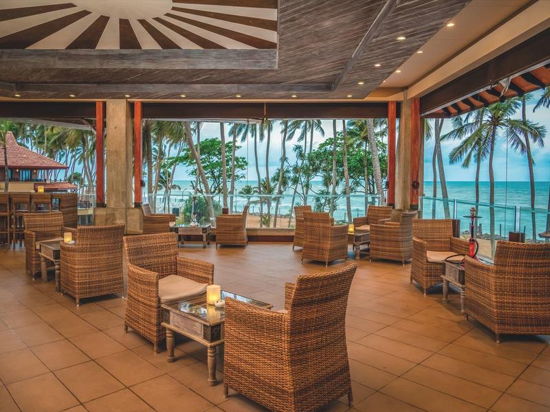 Open lounge met rotan stoelen en uitzicht op zee in een hotel