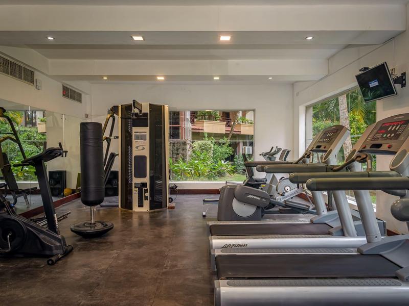 Moderne hotel fitnessruimte met loopbanden, krachtapparaten en uitzicht op tuin.