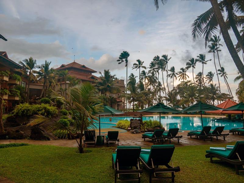 Hotelzwembad met ligstoelen en tropische begroeiing bij schemering