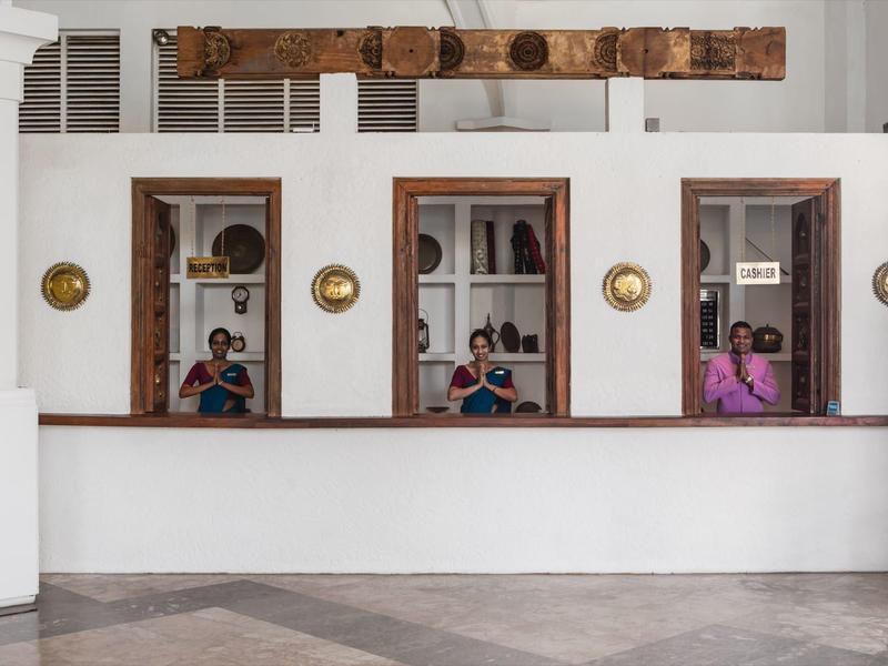 Drie ramen met receptiebalies in hotel, mensen achter balies in kleurrijke kleren.