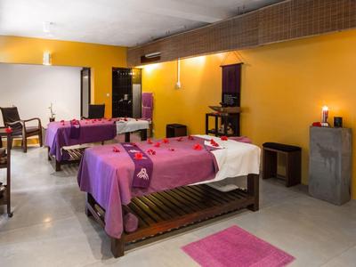 Pokoj se dvěma masážními lehátky, žlutými zdmi a relaxační atmosférou.