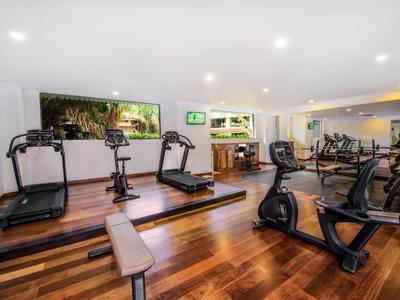 Ein moderner Fitnessraum mit Laufbändern, Fahrrädern und Hanteln auf Holzfußboden.