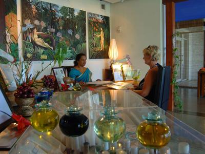 Recepce hotelu s dekorativními lahvemi a dvěma lidmi sedícími u přepážky.