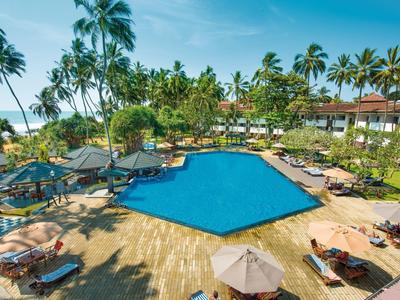 Velký bazén obklopený lehátky a palmami v tropickém hotelovém resortu.