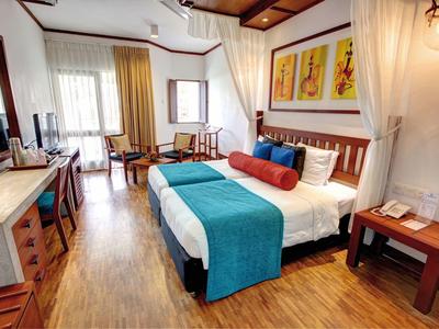 Pohodlný hotelový pokoj s manželskou postelí, modrým přehozem a dřevěným nábytkem