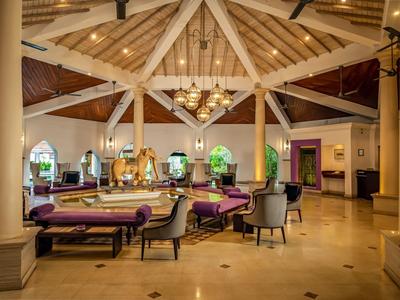 Elegantní hotelová hala s dřevěnými stropy, lustry a útulnými posezeními.