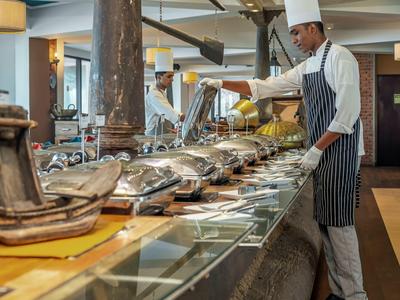 Kuchař v profesionální kuchyni připravuje bufetovou linku s jídlem.