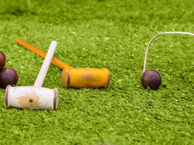 Person steht im Schatten großer Bäume vor einem Hotelgebäude in tropischer Umgebung.
