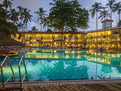 Hotel mit beleuchtetem Pool und Palmen bei Dämmerung
