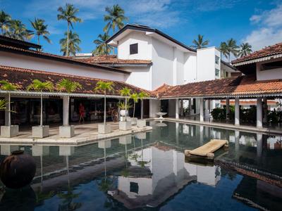 Moderní hotelová bazénová oblast s lehátky a palmami pod modrou oblohou.