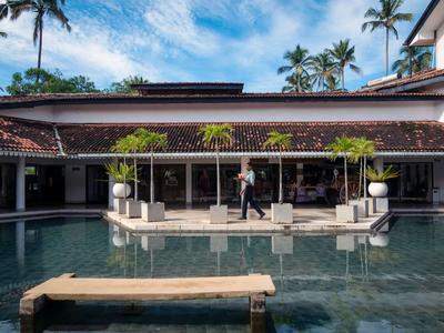 Moderní hotelový bazén s palmami a odpočinkovou zónou pod modrou oblohou.