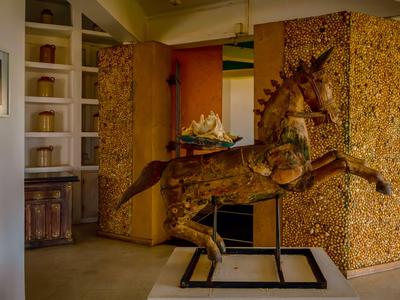 Detailreiche Holzfigur eines galoppierenden Pferdes in einem warm beleuchteten Innenraum.