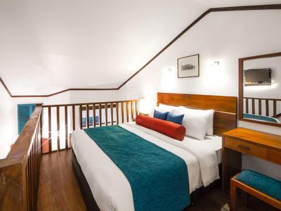 Přátelský hotelový pokoj s manželskou postelí a dřevěnou výzdobou pod šikmým stropem.