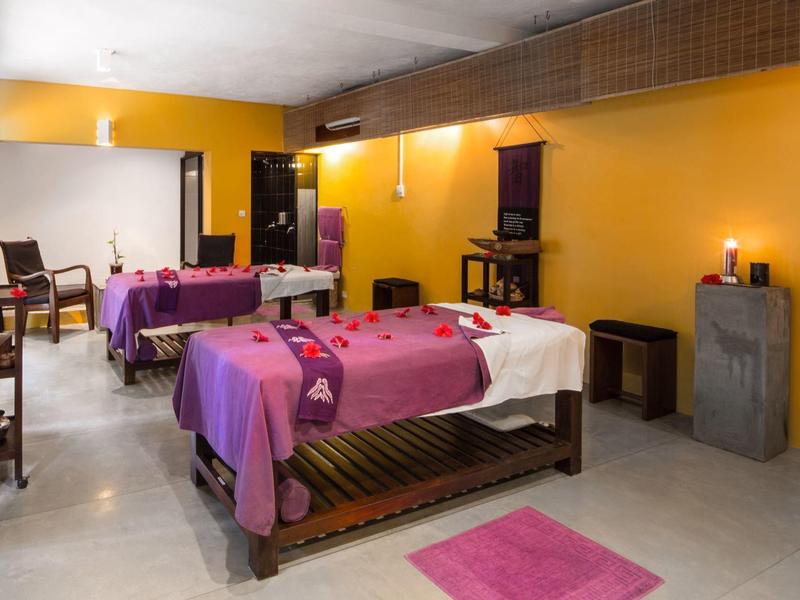 Pokoj se dvěma masážními lehátky, žlutými zdmi a relaxační atmosférou.