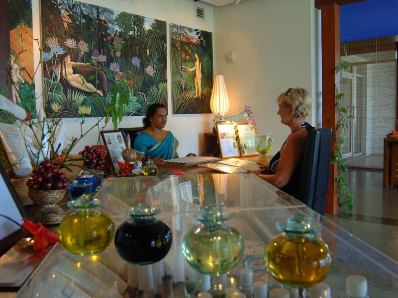 Recepce hotelu s dekorativními lahvemi a dvěma lidmi sedícími u přepážky.