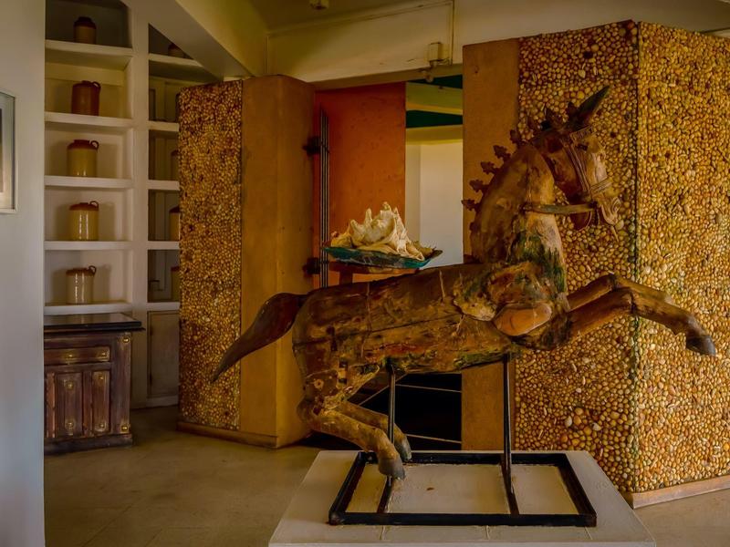 Dřevěná socha koně v hotelovém pokoji s rustikálním vybavením.