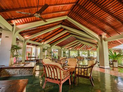 Offener, gemütlicher Sitzbereich mit Holzdach, großen Fenstern und Rattanstühlen in natürlicher Farbe.