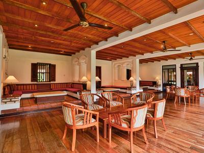 Großer Raum mit Holzboden, Holztischen und Stühlen, hoher Decke mit Ventilatoren, warmes Holzambiente.