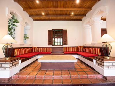 Gemütlicher Sitzbereich mit rotem Polstersofa, weißen Wänden und hölzernem Deckengebälk.