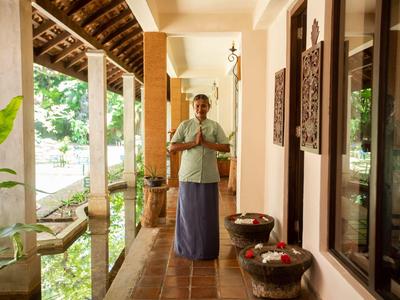Ein Mann steht auf einem überdachten Balkon mit dekorativen Schalen und Fenstern an der Wand.