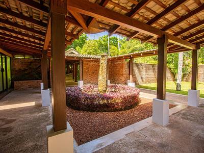 Überdachter Innenhof mit Garten und Blumenbeet, umgeben von Holzbalken und Ziegelwand.