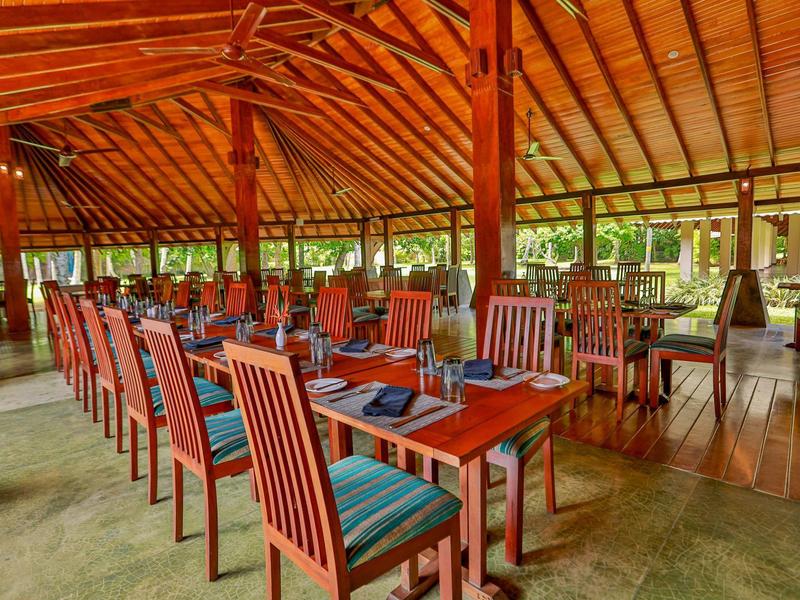 Großes Restaurant mit hölzernen Deckenbalken, roten Stühlen und blau gestreiften Polstern.