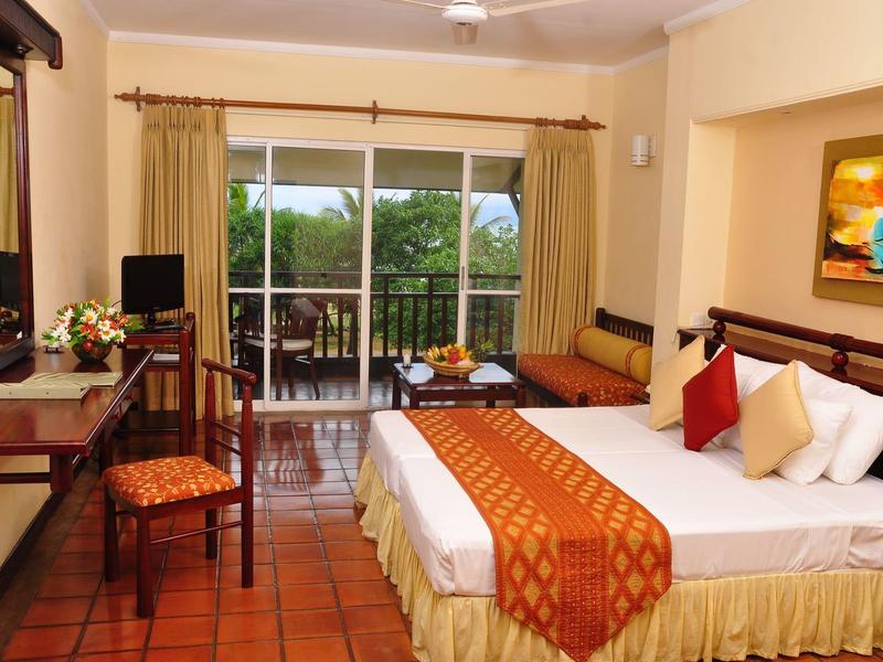 Gemütliches Hotelzimmer mit Doppelbett, Holzmöbeln, Balkon und warmen Erdtönen.