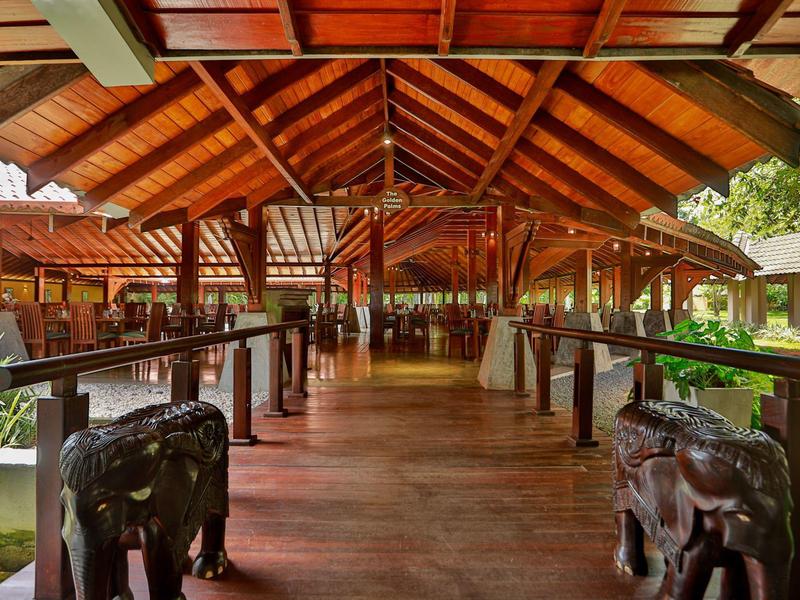 Großer Holzpavillon mit geschnitzten Elefantenstatuen, Dach aus Holzbalken und Holzboden.