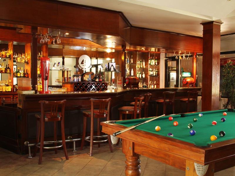 Hotel bar with dark wood, stools, and a green pool table in the foreground