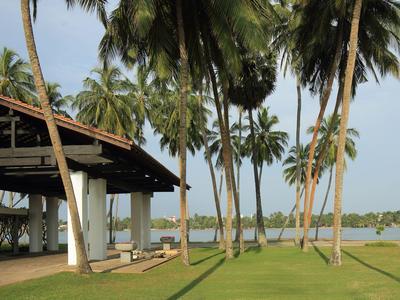 Hotel mit Säulen unter einer überdachten Terrasse und Palmen in der Nähe eines Strandes.