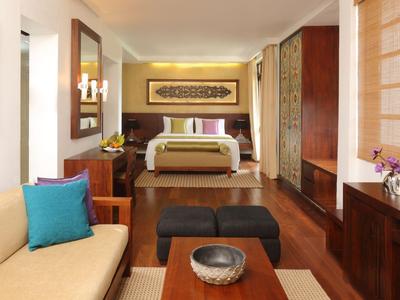 Modern eingerichtetes Hotelzimmer mit Bett, Couch und Flachbildfernseher.