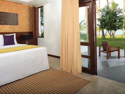 Hotelzimmer mit Bett und Terrasse mit Blick auf Garten und Meer