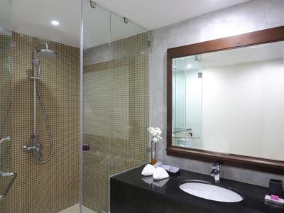 Moderner Hotelbadezimmer mit Glasdusche, schwarzer Theke und großem Spiegel.