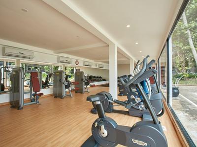 Fitnessraum mit modernen Trainingsgeräten und großen Fenstern mit Blick nach draußen.