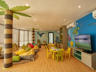 Heller, bunter Kinderspielraum mit Holzfußboden, Sitzsäcken, Tischen und Wanddekoration mit Meerestieren.