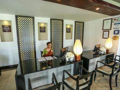 Rezeption mit zwei Mitarbeitern, Empfangstresen und Sitzbereich in einem Hotel.