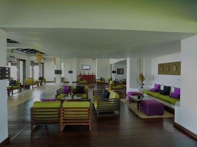 Moderner Hotellobby-Bereich mit Holzboden, Sitzgruppen aus Holz und bunten Kissen.