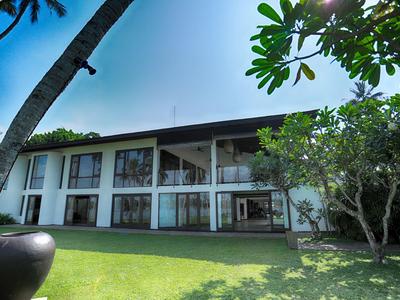 Modernes zweistöckiges Hotelgebäude mit großen Fenstern und gepflegtem Garten unter blauem Himmel.
