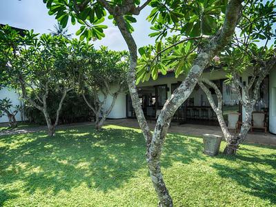 Grüner Innenhof mit Bäumen vor einem weißen Gebäude mit Holztüren.