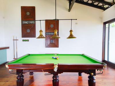 Ein Billardtisch in einem hellen Raum mit Holzfußboden, Hängelampen und Fenster.