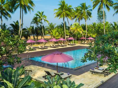 Hotelpool mit rosa Sonnenschirmen, Liegestühlen und Palmen im tropischen Garten.