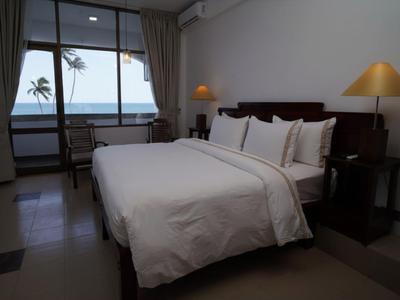 Hotelzimmer mit großem Bett, Schreibtisch und Meerblick durch ein großes Fenster.