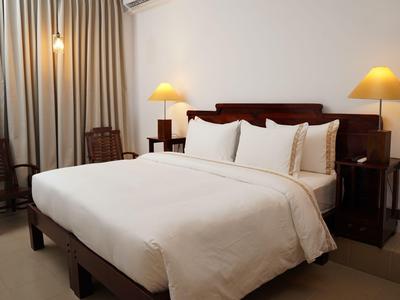Elegantes Hotelzimmer mit großem Bett, weißen Bettwaren und zwei Nachttischen mit Lampen.