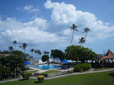 Tropische Hotelanlage mit Pool, Palmen und strahlend blauem Himmel an einem sonnigen Tag.